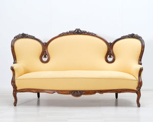 Antiikkinen sohva keltaisella verhoilulla